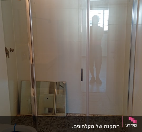 חדר אמבטיה עם מקלחון ודלת זכוכית